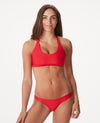 Woman in cross back bright red bikini against white background.