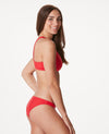 Woman in cross back bright red bikini against white background.