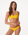 Woman in bright yellow bikini against white background.