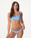 Woman in T-strap back light blue bikini against white background.