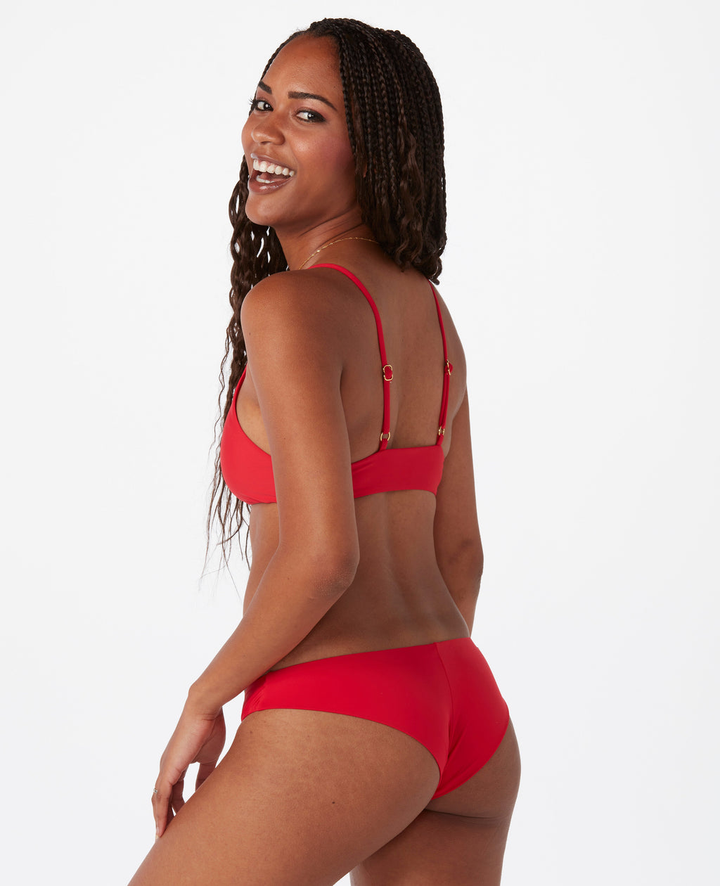 Woman against white background laughing, wearing a bright red bikini.