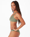 Smiling woman with brown hair in a sage bikini against a white background.