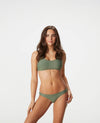 Smiling woman with brown hair in a sage bikini against a white background.